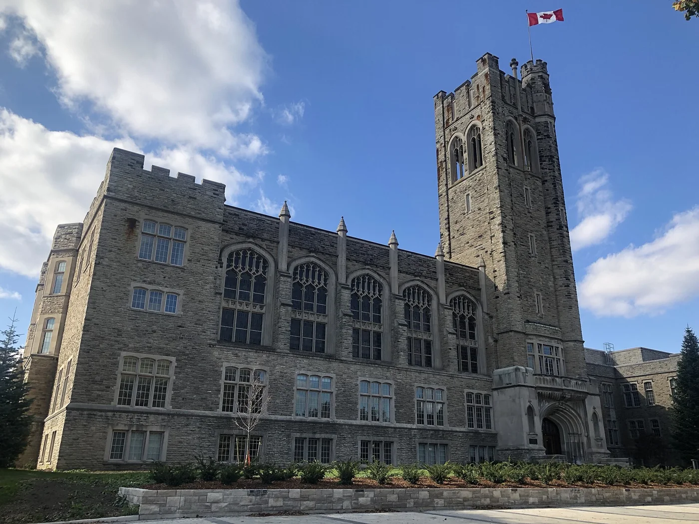 A collegiate-gothic university tower on a green hill in autumn light